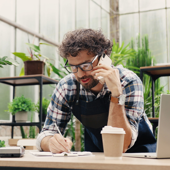 A small business owner talking on the phone and writing notes.