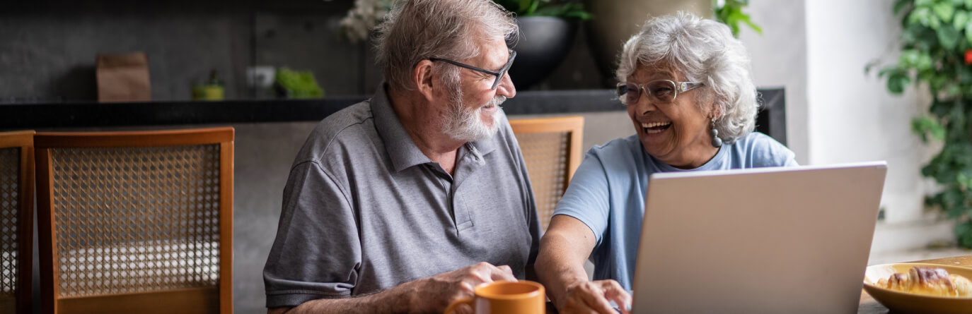 Mature couple smiling while using laptop