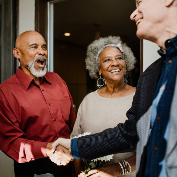 Mature friends greeting one another at the door