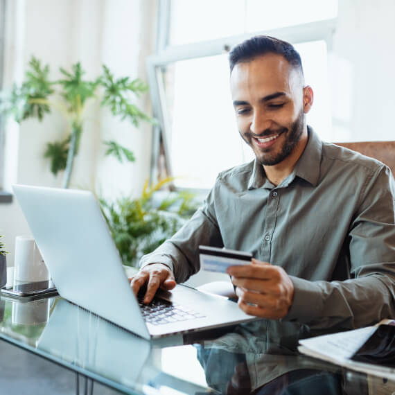 man holding card at desk with laptop