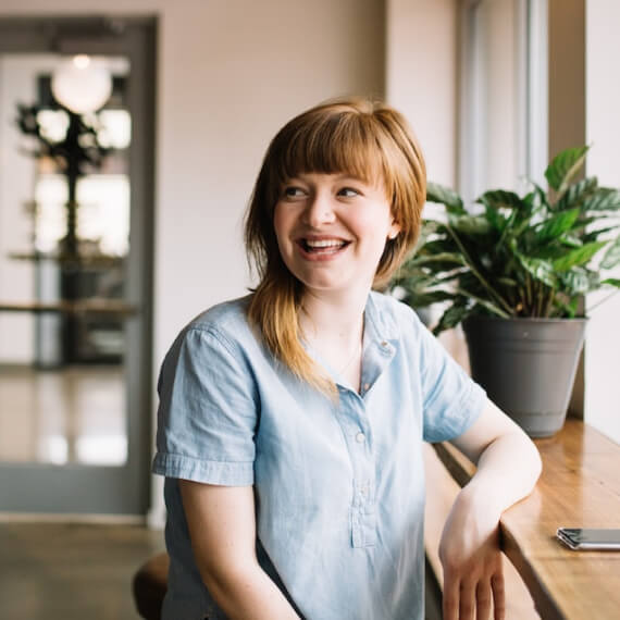 young woman smiling, looking into distance at coffee shop