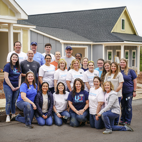 Group photo of United Bank employees standing in front of houses outside.