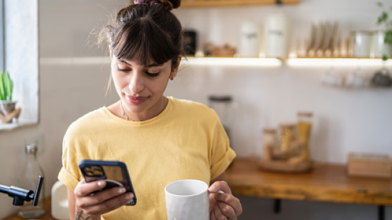 Woman drinking coffee and using mobile phone