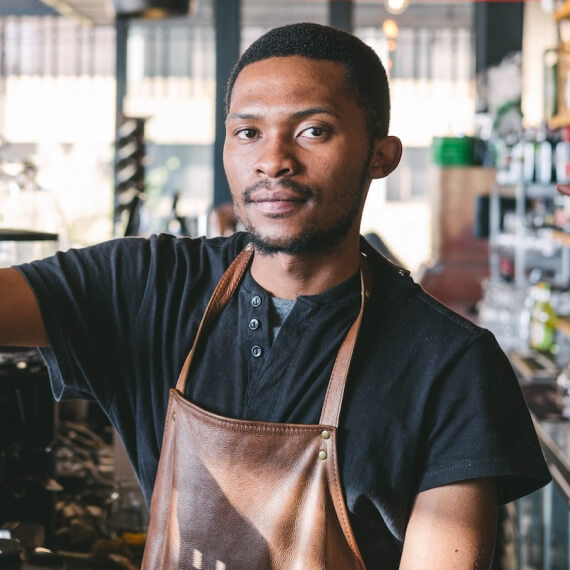 young man with apron behind a counter at a business