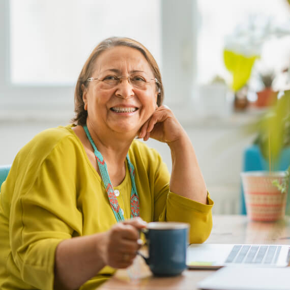 happy woman smiling with coffee at desk